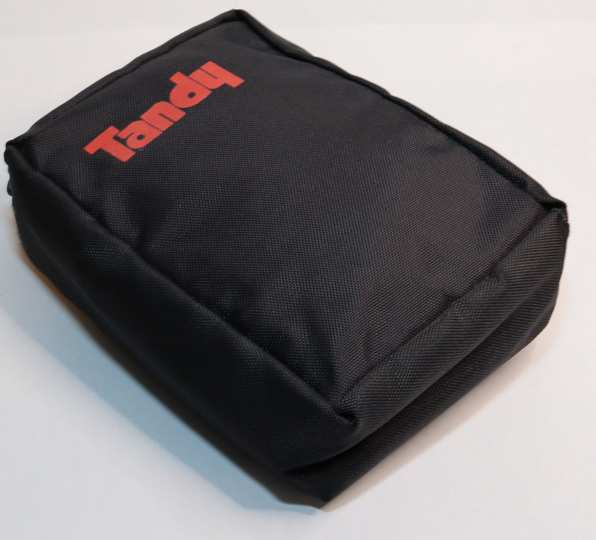 A black fabric pouch with the brand name 'Tandy' printed in red on the front, photographed on a white surface.